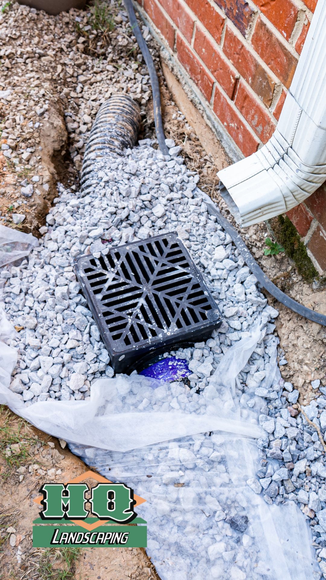 drainage image A professionally installed drainage system with a black catch basin, gravel, and a connected downspout, showcasing HQ Landscaping's expert drainage solutions to prevent water damage.